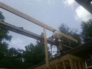 Carpenter setting a ridge beam over a new addition frame — Ice Dam Removal by Roofing Brothers in Crump