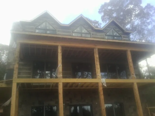 Dormers and porch framing on a large log home under construction — Roof Coating work by our crew in Crump
