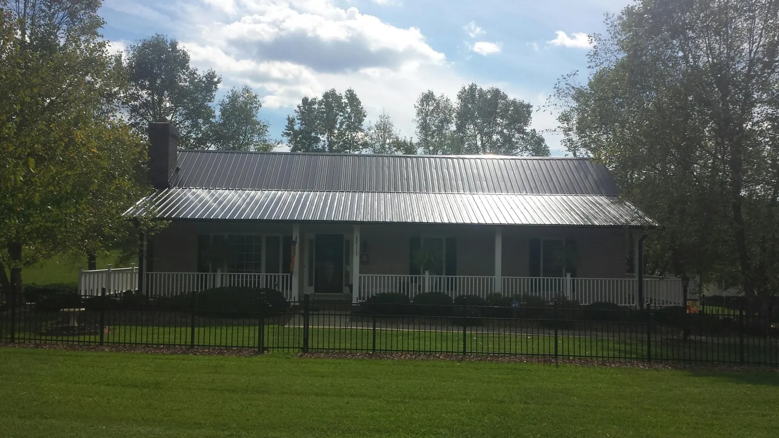 Gray metal roof on a brick ranch with a full width front porch — Gutter Guard Installation work by our crew in Crump