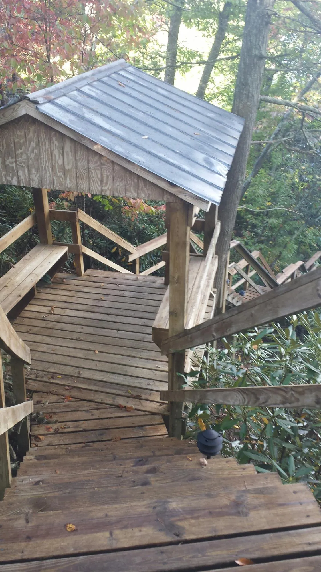 Metal roofed shelter over wooden steps on a wooded walkway — Skylight Repair & Installation work by our crew in Crump
