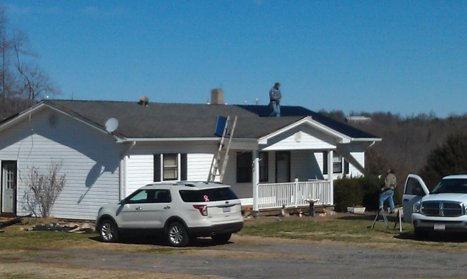 Roofers stripping shingles from a white ranch house roof in Crump