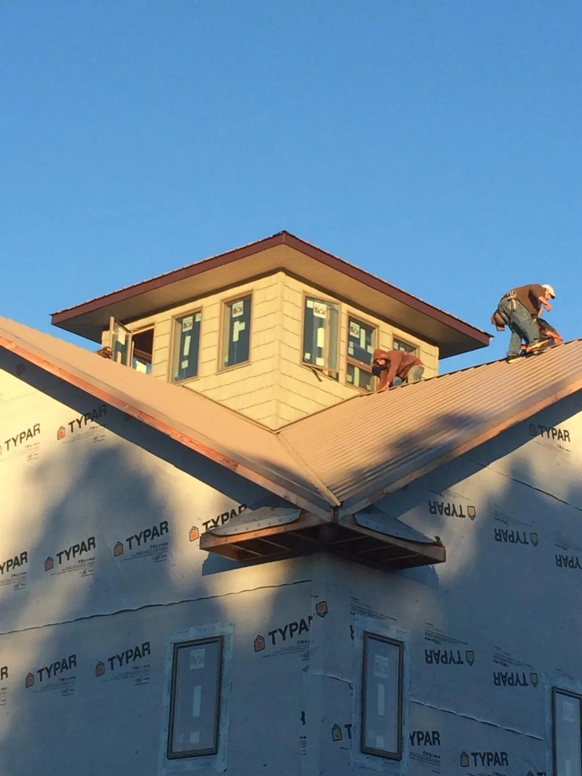 Roofers working around a rooftop cupola on a new metal roof at sunset — Roof Waterproofing in Crump by Roofing Brothers